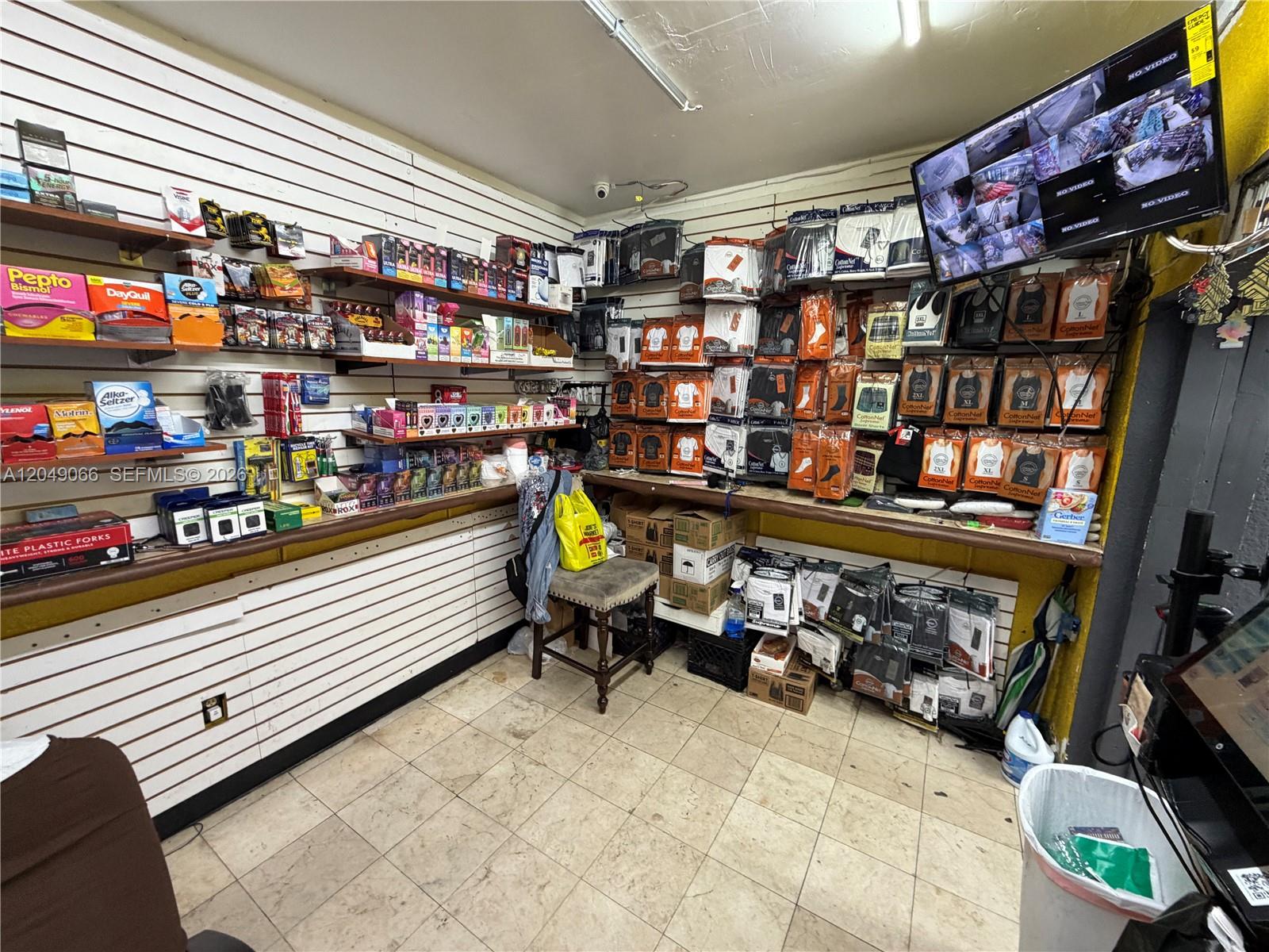 A small retail shop features white slat walls, shelves stocked with merchandise, and a security monitor — 4980 NW 22nd Ave, Miami FL 33142, MIAMI, FL