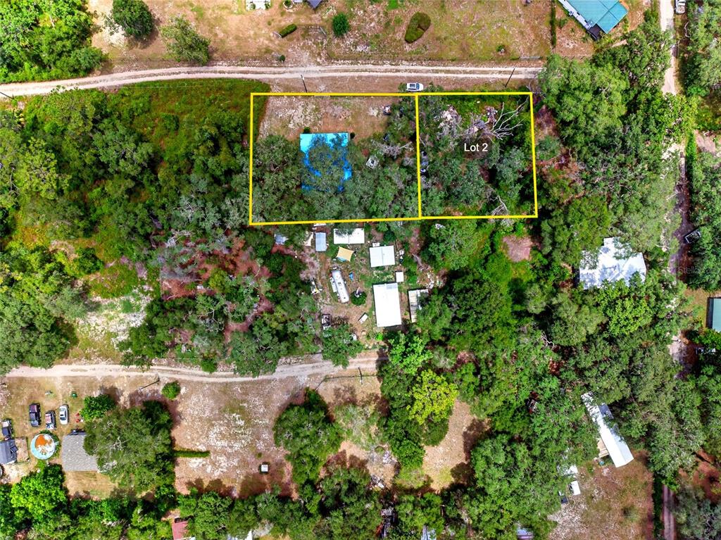 This aerial view shows two adjacent wooded lots, one with a blue-roofed structure — 18938 SE 105TH LANE, OCKLAWAHA, FL