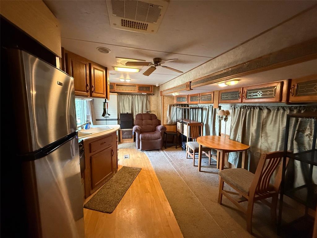 A kitchen and dining area inside a mobile home with wood cabinets and laminate flooring — 3000 CLARCONA ROAD UNIT 2011, APOPKA, FL