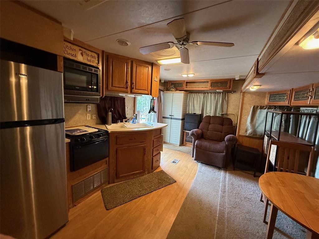 A kitchen and living area in a mobile home with wood cabinets and a recliner — 3000 CLARCONA ROAD UNIT 2011, APOPKA, FL