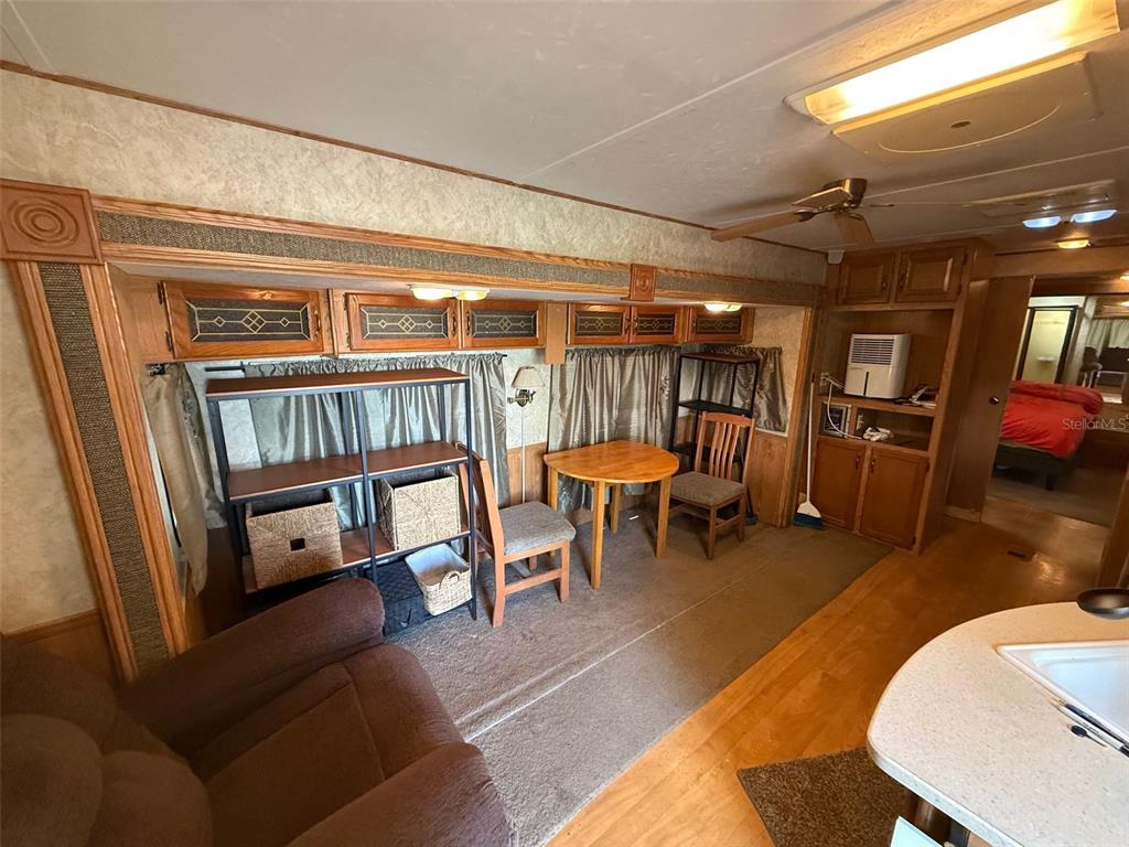 A living area in a mobile home features a dining table, shelving, and wood cabinetry — 3000 CLARCONA ROAD UNIT 2011, APOPKA, FL