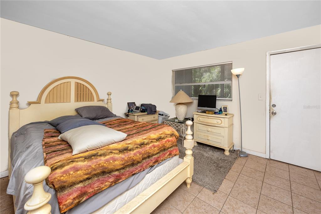 A bedroom features a bed with a wooden headboard, tiled floors, and a white door — 224 WAVERLY WAY UNIT 4, CLEARWATER, FL