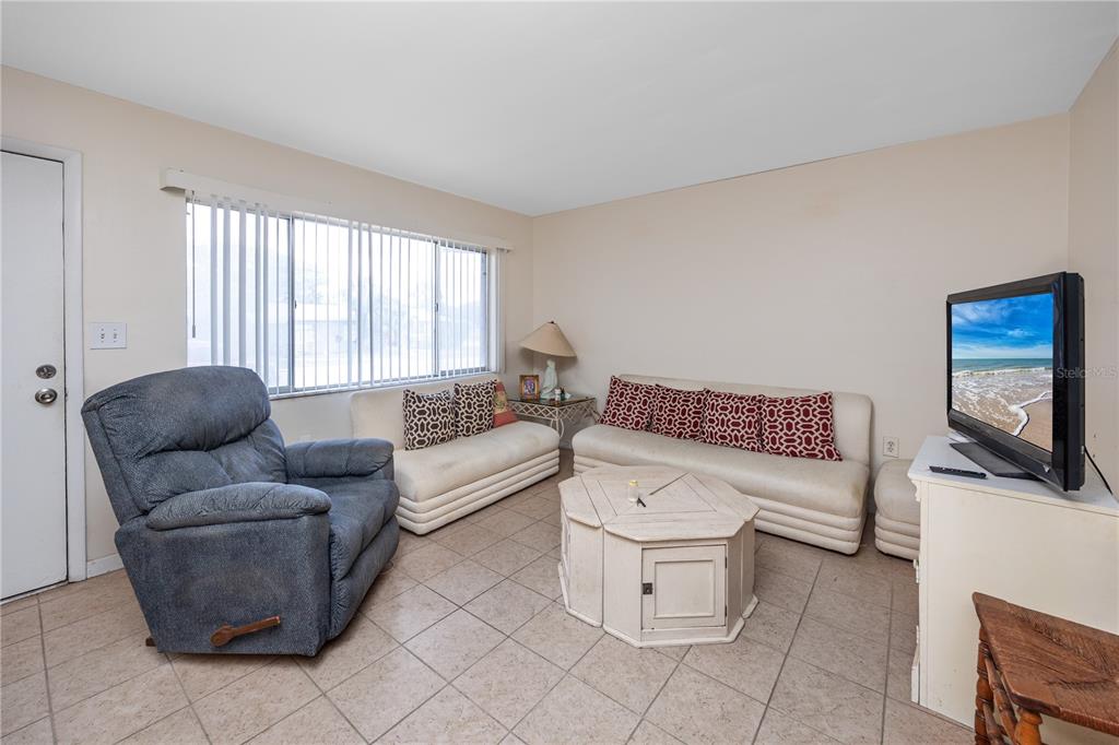 A living room features tile flooring, a blue recliner, two white sofas, and a television — 224 WAVERLY WAY UNIT 4, CLEARWATER, FL