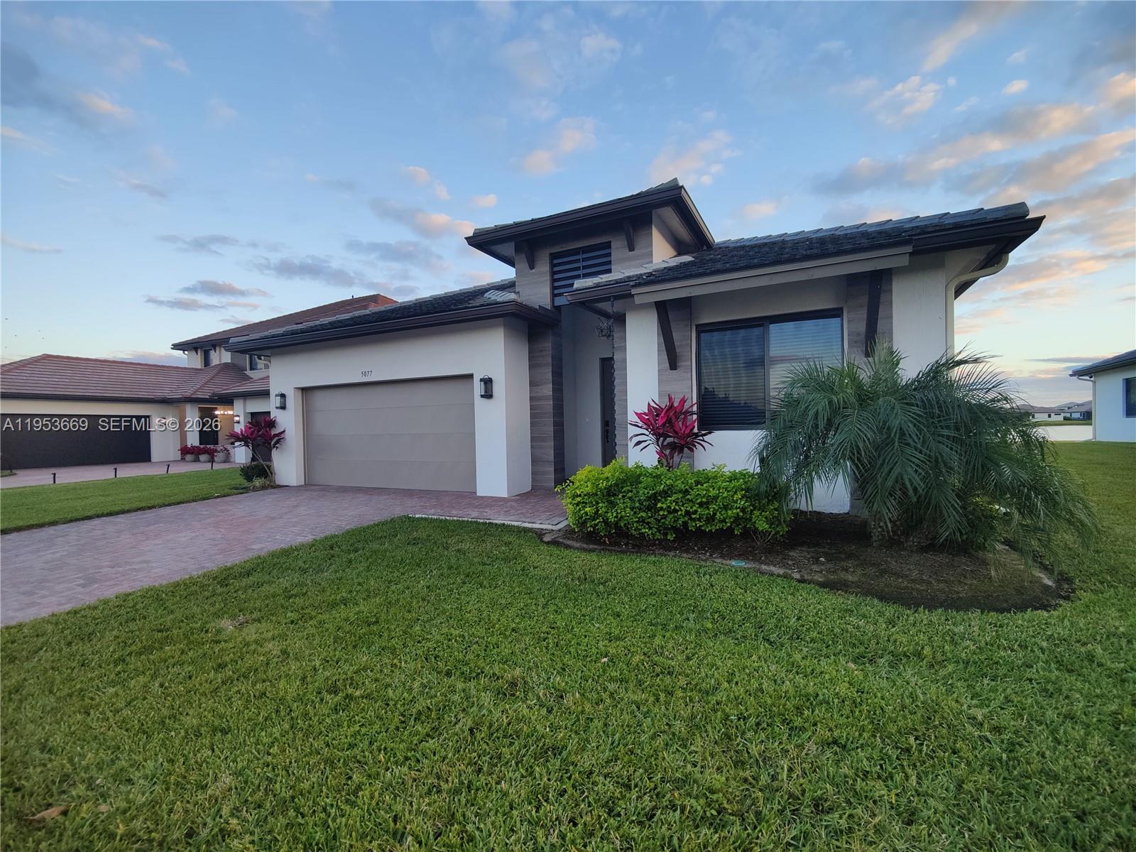 A modern single-story house with a two-car garage, paved driveway, and landscaped front yard — 5077 Gambero Way # 5077, Naples FL 34142, NAPLES, FL