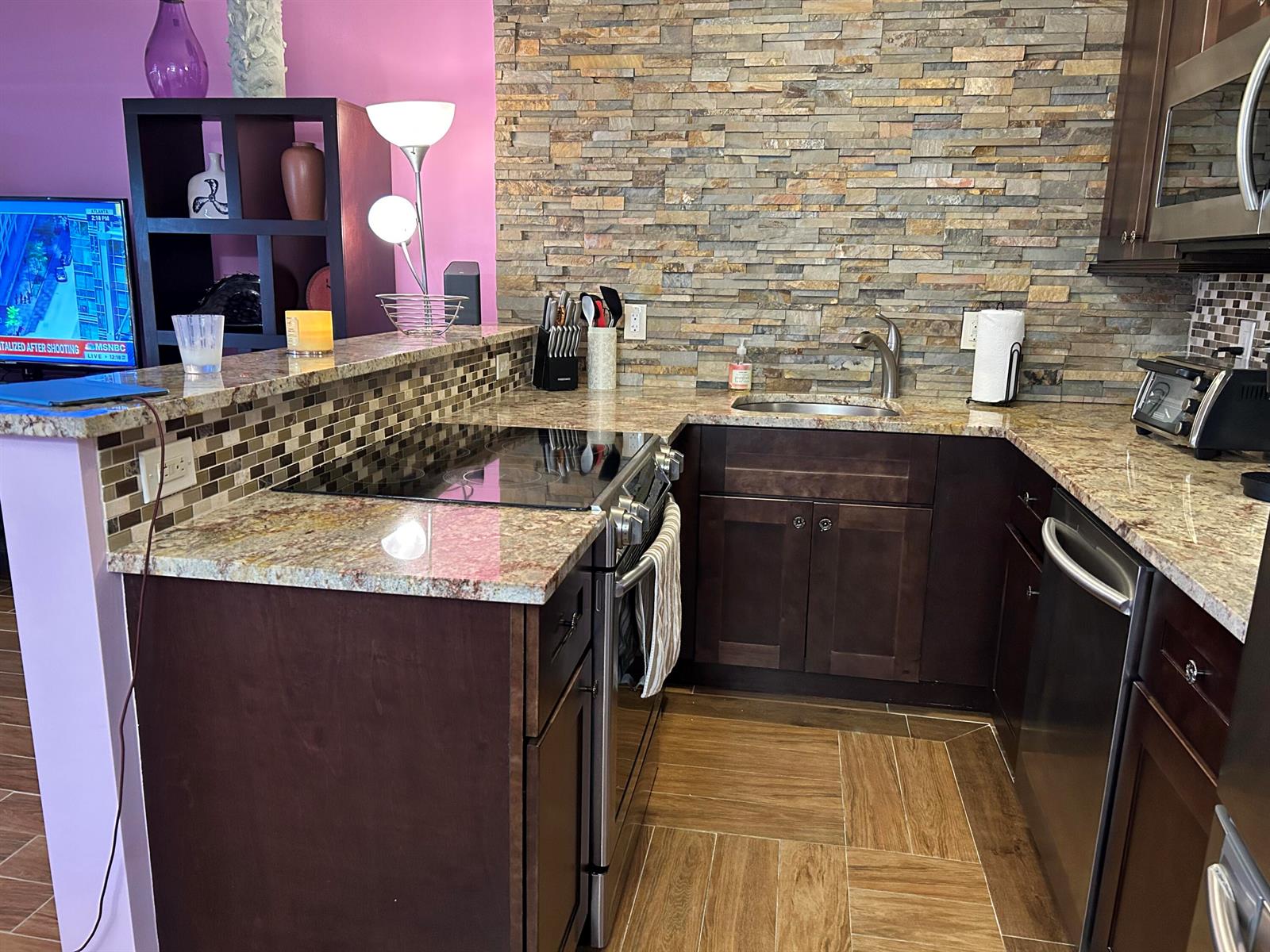 A kitchen features dark wood cabinets, granite countertops, a stone backsplash, and stainless steel appliances — 3070 Cornwall D # D, Boca Raton FL 33434, BOCA RATON, FL