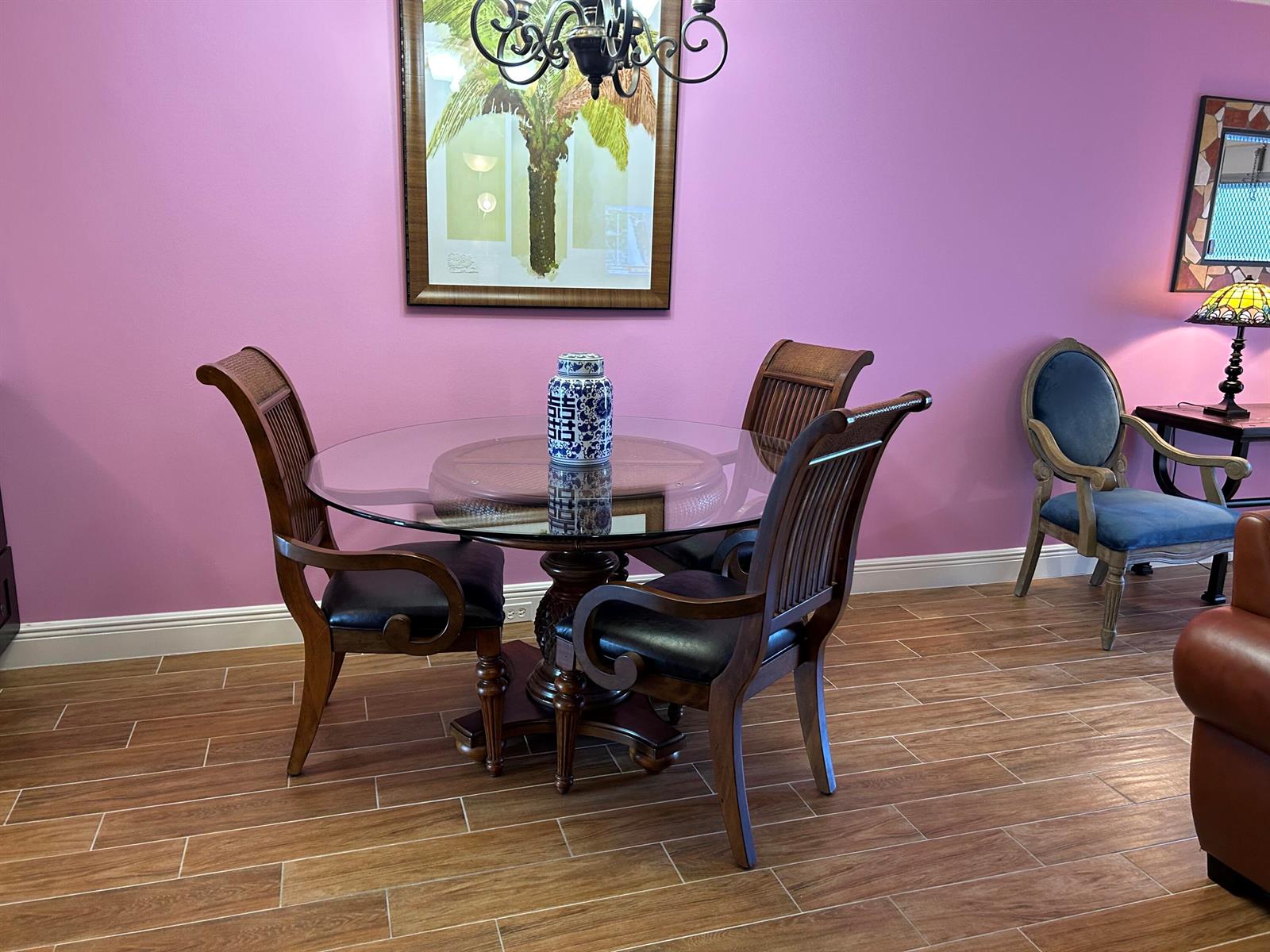 A dining area features a round glass table, four wooden chairs, and pink walls — 3070 Cornwall D # D, Boca Raton FL 33434, BOCA RATON, FL