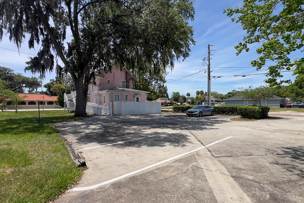 A pink two-story building sits behind a paved parking lot with marked spaces — 821 EMMETT STREET 2nd Floor, KISSIMMEE, FL