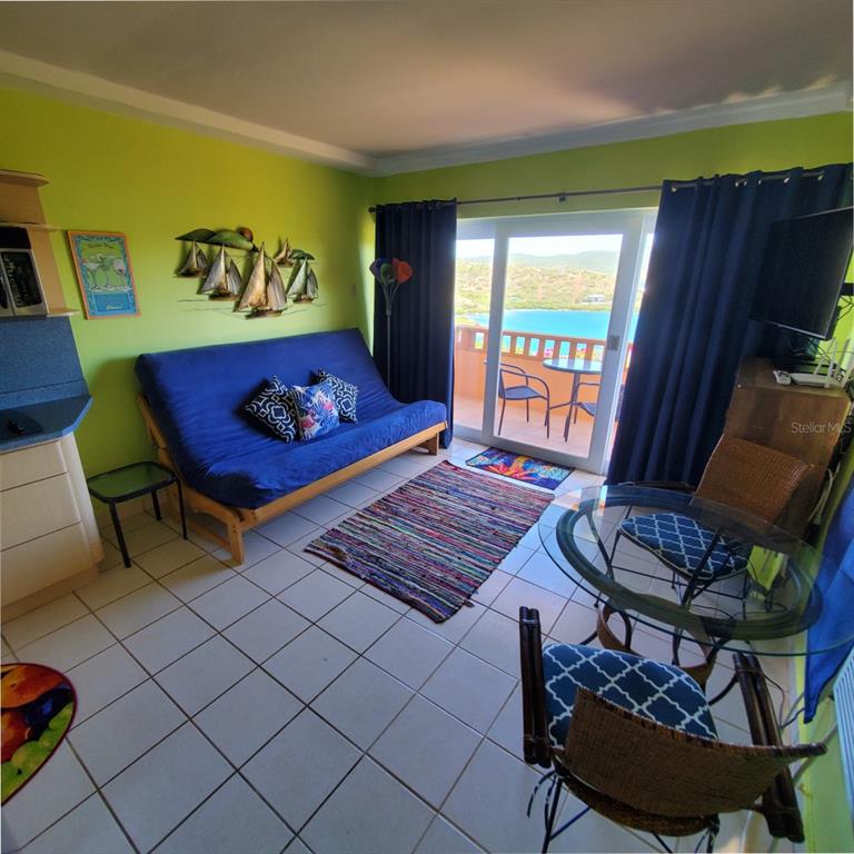 A living room with a blue futon, dining set, and sliding doors opening to a balcony — C101 BAHIA MARINA CONDOMINIUM RESORT UNIT C101, CULEBRA, PR