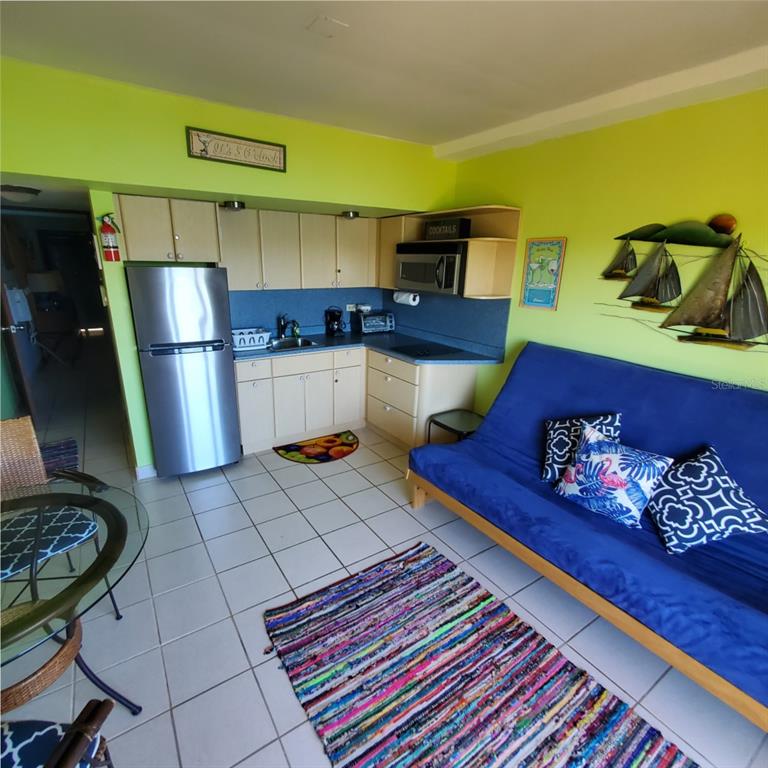 A small kitchen with stainless steel appliances sits next to a blue futon in a room — C101 BAHIA MARINA CONDOMINIUM RESORT UNIT C101, CULEBRA, PR