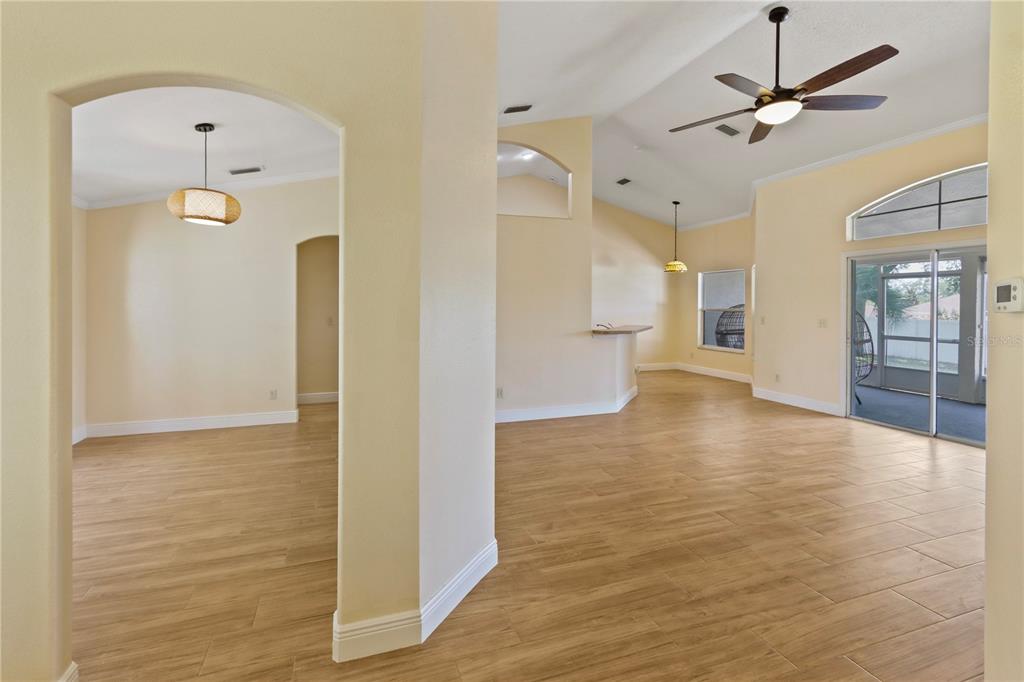 An open-concept living area features light-colored walls, wood-look tile flooring, and a vaulted ceiling — 10814 VINEYARD COURT, CLERMONT, FL