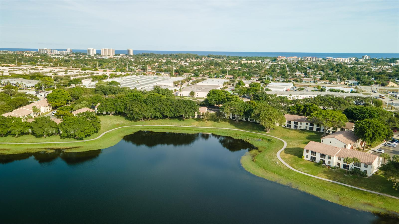 An aerial view shows a lake surrounded by apartment buildings and lush green landscaping — 2900 Olivewood Terrace # 2010, Boca Raton FL 33431, BOCA RATON, FL