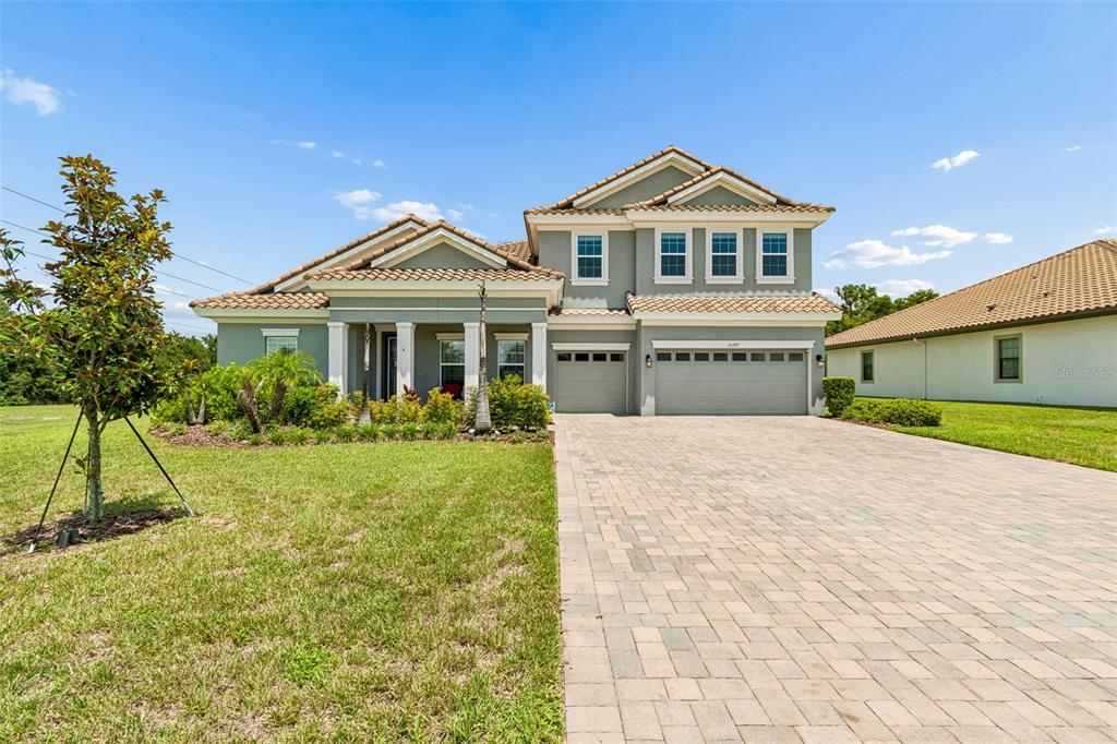 A two-story suburban house with a gray exterior, tiled roof, and a paved driveway — 10597 MEADOWRUN DRIVE, LITHIA, FL
