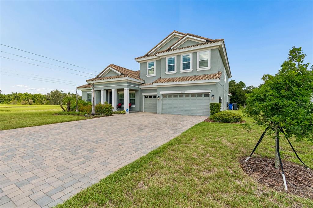 A two-story house with a light green exterior, tiled roof, and a paved driveway — 10597 MEADOWRUN DRIVE, LITHIA, FL