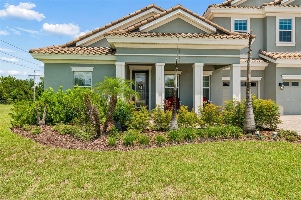 A front porch features a dark gray door with a glass insert and a welcome mat — 10597 MEADOWRUN DRIVE, LITHIA, FL