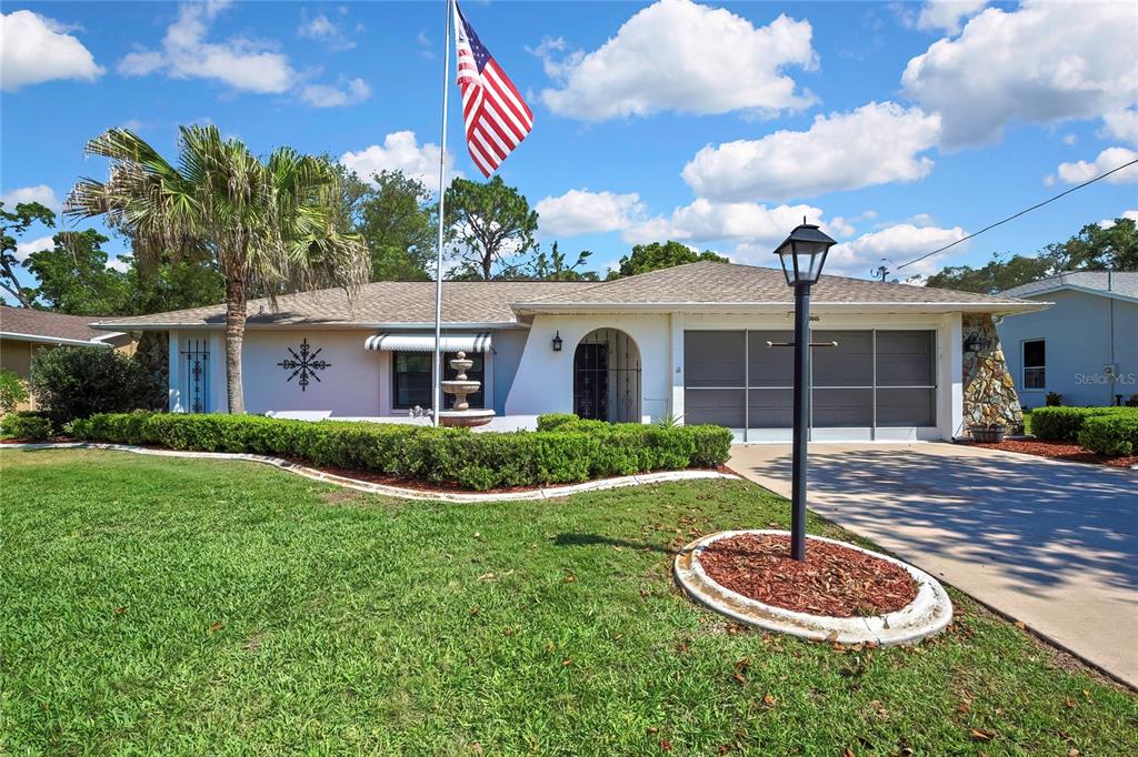 A single-story house features a white exterior, a two-car garage, and a front lawn — 9045 GAYNOR STREET, SPRING HILL, FL