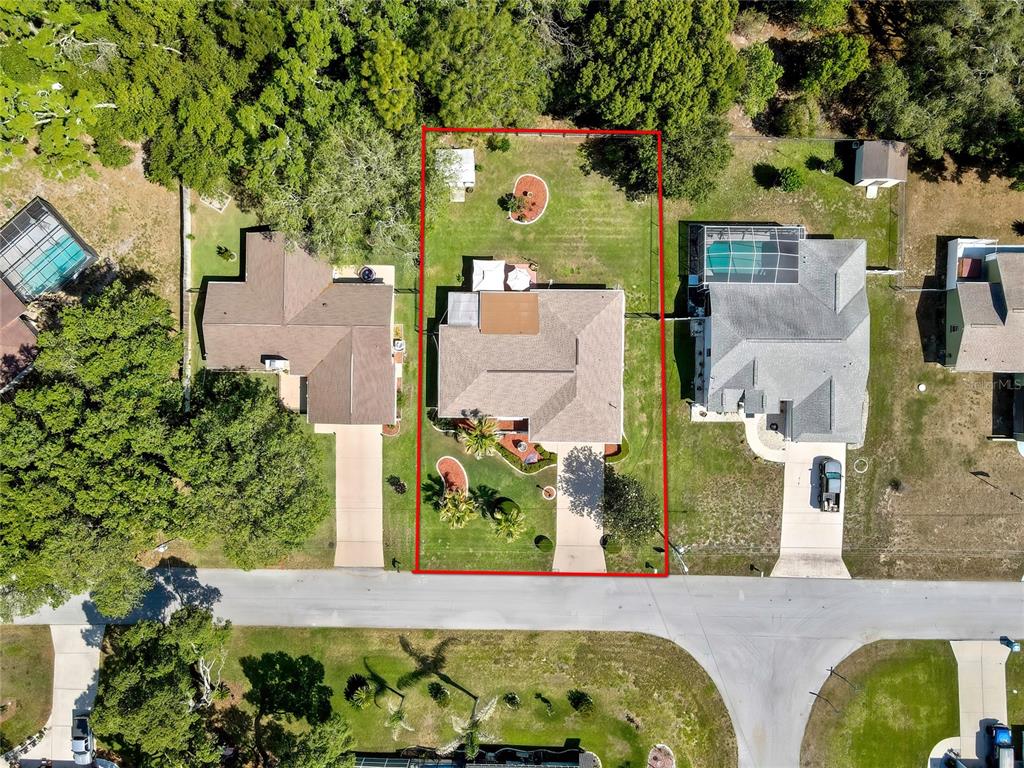 An aerial view shows a single-family home with a large backyard and driveway — 9045 GAYNOR STREET, SPRING HILL, FL