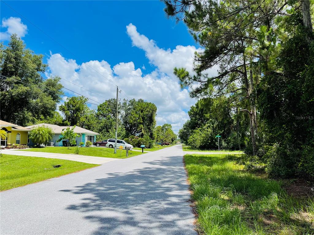 A paved residential street lined with houses, trees, and a grassy roadside under a blue sky — Lot 2 ALWOOD STREET, NORTH PORT, FL