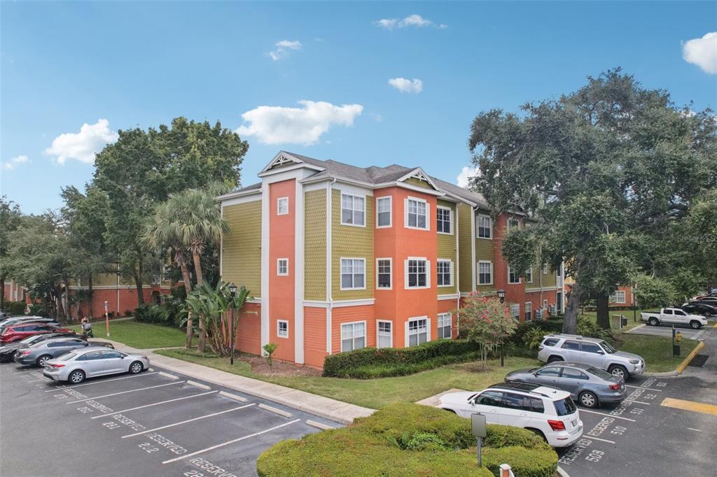 A three-story apartment building with orange and green siding stands next to a parking lot — 4207 S DALE MABRY HIGHWAY UNIT 11207, TAMPA, FL