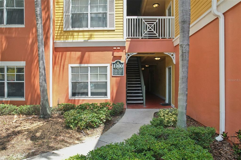 An exterior view of an apartment building entrance with stairs leading to upper units — 4207 S DALE MABRY HIGHWAY UNIT 11207, TAMPA, FL