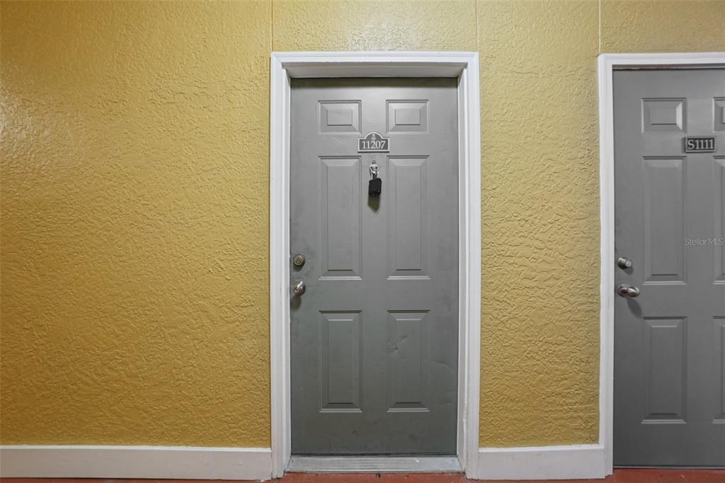 Two gray apartment doors with unit numbers and lockboxes are set against a yellow wall — 4207 S DALE MABRY HIGHWAY UNIT 11207, TAMPA, FL