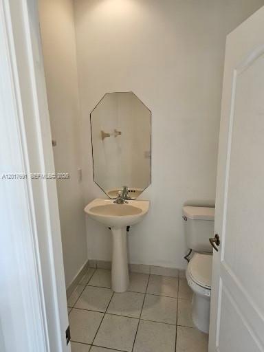 A small bathroom features a pedestal sink, an octagonal mirror, and a white toilet — 2160 NE 37th Rd, Homestead FL 33033, HOMESTEAD, FL
