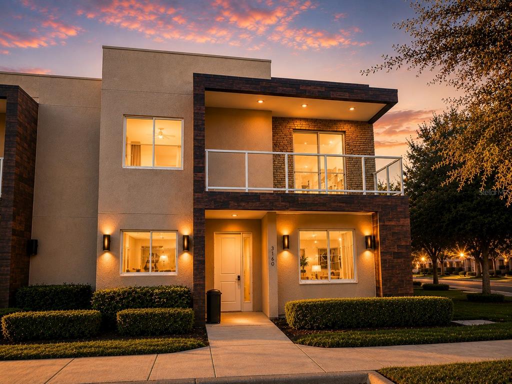 A two-story modern townhouse exterior features a balcony, stone accents, and a front walkway — 3160 PANTANAL LANE, KISSIMMEE, FL