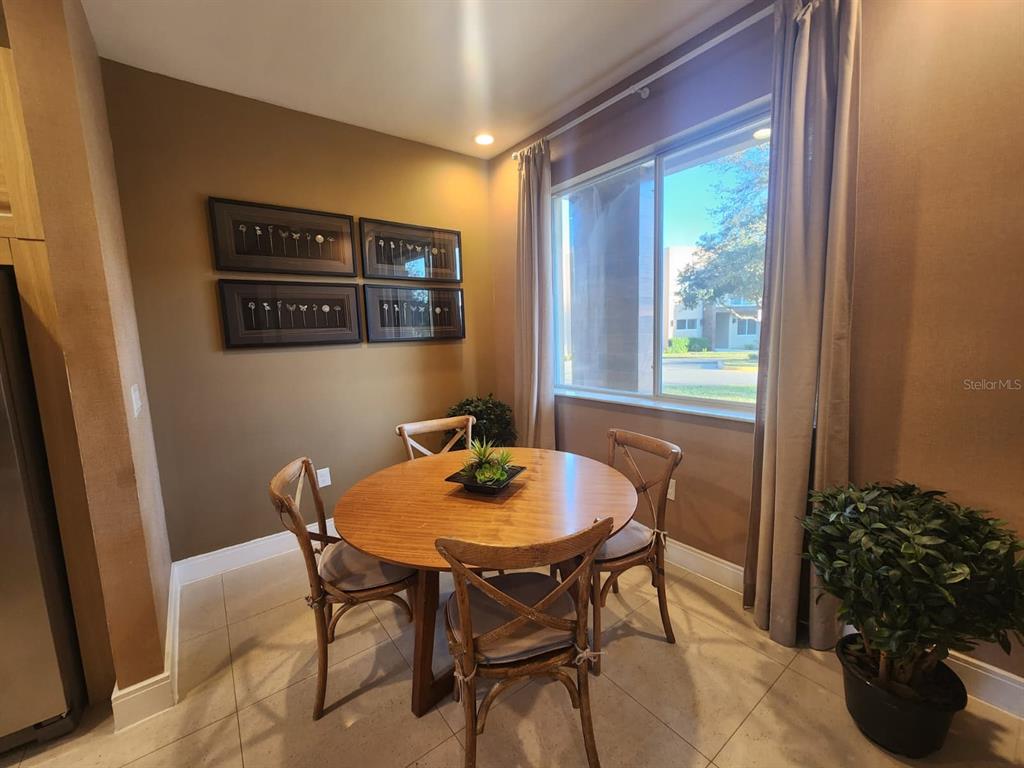 A dining nook features a round wooden table, four chairs, and framed wall art — 3160 PANTANAL LANE, KISSIMMEE, FL