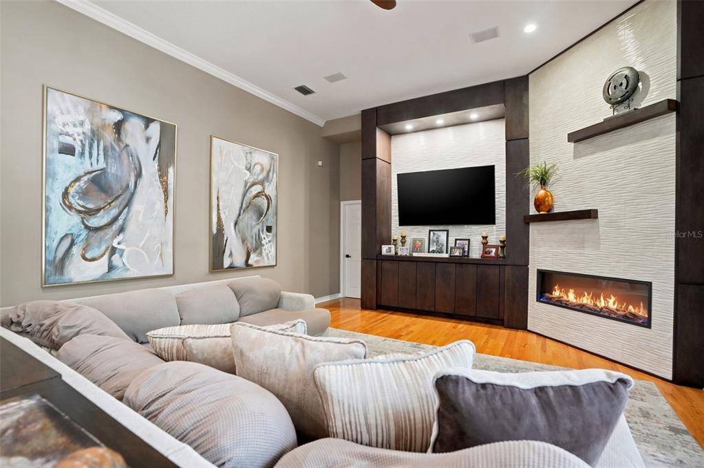 A living room features a large sectional sofa, a wall-mounted television, and a linear fireplace — 30218 FAIRWAY DRIVE, WESLEY CHAPEL, FL
