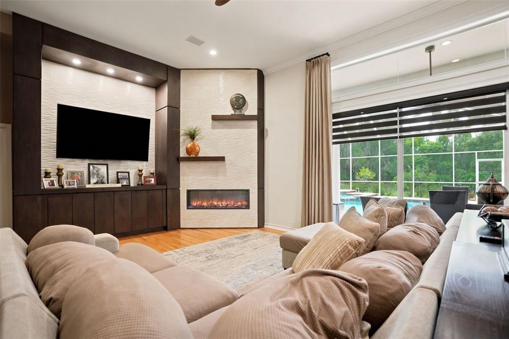 A living room features a large sectional sofa, a corner fireplace, and a built-in media center — 30218 FAIRWAY DRIVE, WESLEY CHAPEL, FL