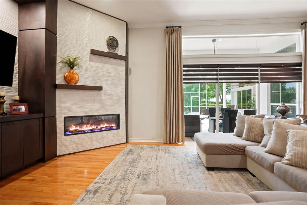 A living room features a linear fireplace, textured wall, floating shelves, and a large sectional — 30218 FAIRWAY DRIVE, WESLEY CHAPEL, FL