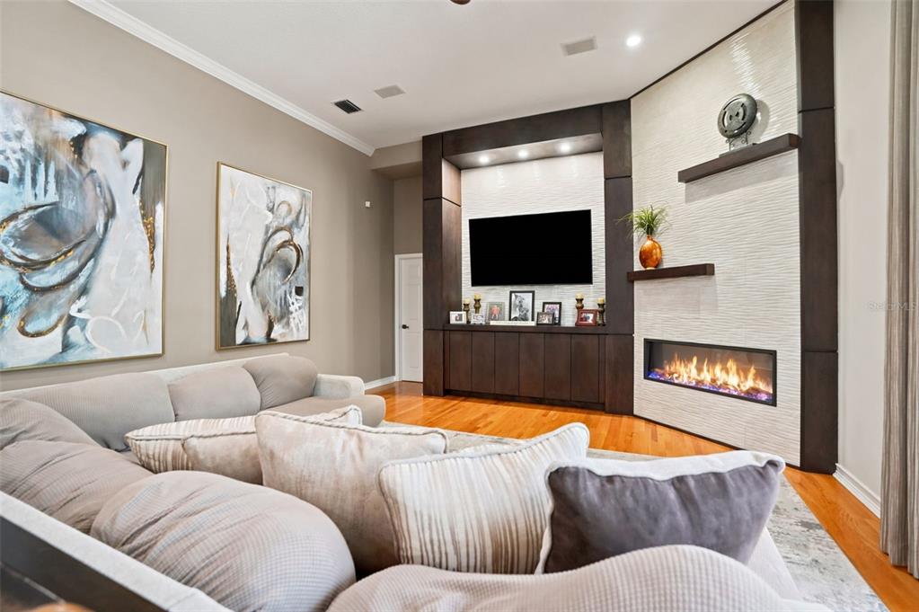A living room features a large sectional sofa, hardwood floors, and a built-in media wall — 30218 FAIRWAY DRIVE, WESLEY CHAPEL, FL