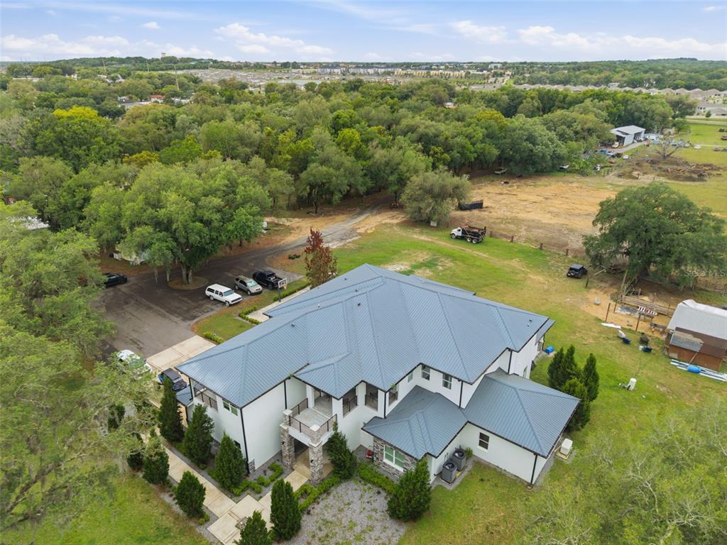 An aerial view shows a large white house with a dark metal roof and driveway — 8241 CASS ROAD, ZEPHYRHILLS, FL
