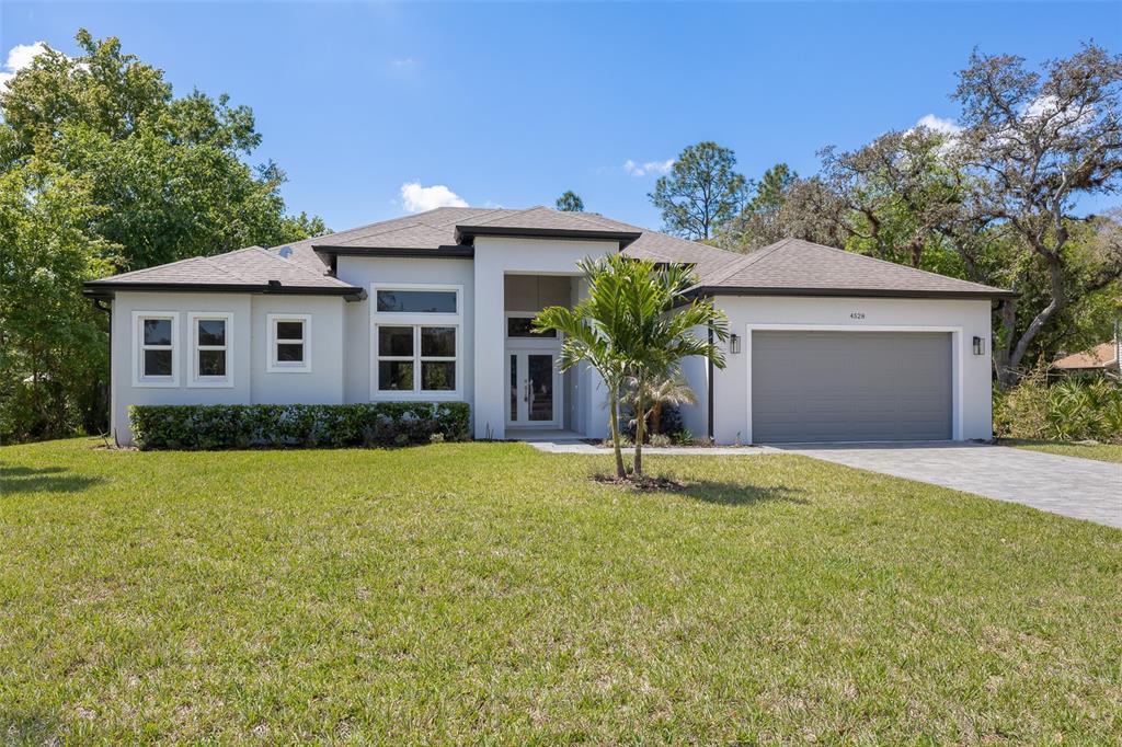 A single-story house with a gray garage, white stucco exterior, and a paved driveway — 4531 YORKSHIRE LANE, KISSIMMEE, FL