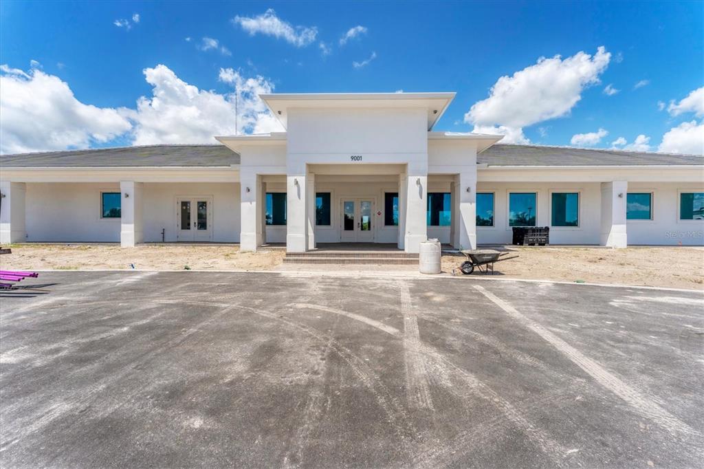 A wide-angle exterior view of a single-story white commercial building with a paved parking lot — 9001 GASPARILLA ROAD UNIT 87, PLACIDA, FL