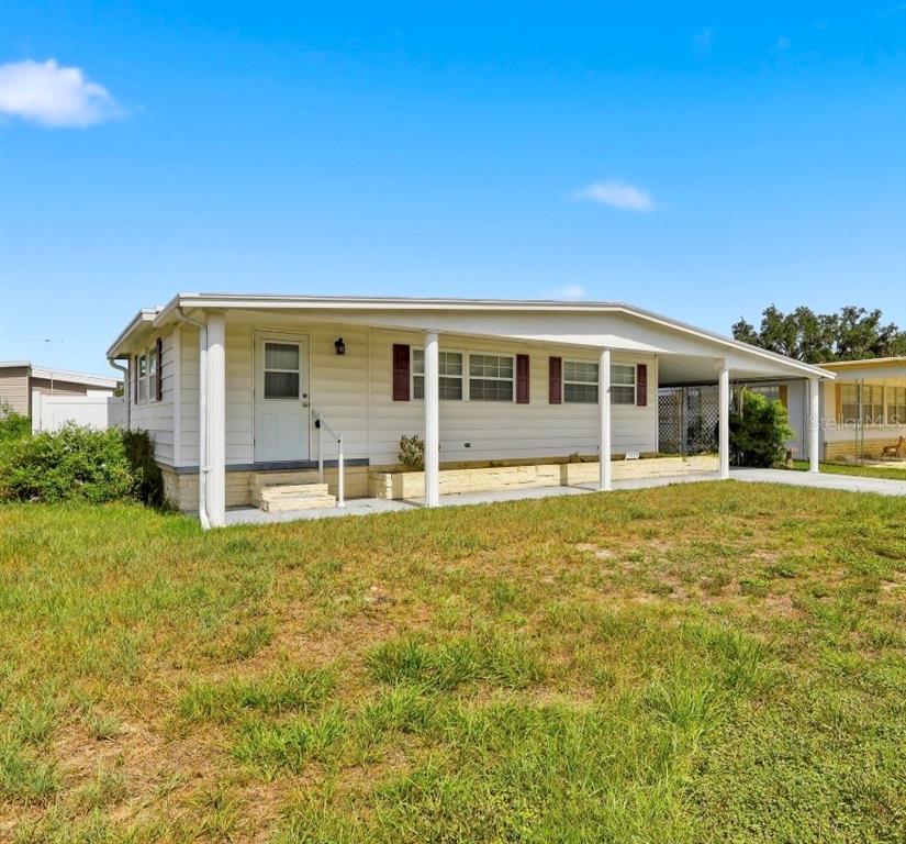 A single-story manufactured home with white siding, a covered porch, and a carport — 5417 AMANDA STREET, ZEPHYRHILLS, FL