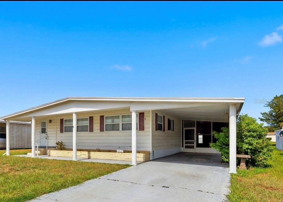 A single-story manufactured home with light siding, a carport, and a front lawn — 5417 AMANDA STREET, ZEPHYRHILLS, FL