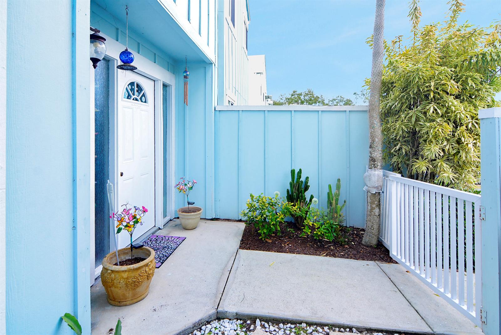 A light blue house exterior features a white front door, a concrete patio, and cacti — 6198 Riverwalk Lane # 2, Jupiter FL 33458, JUPITER, FL