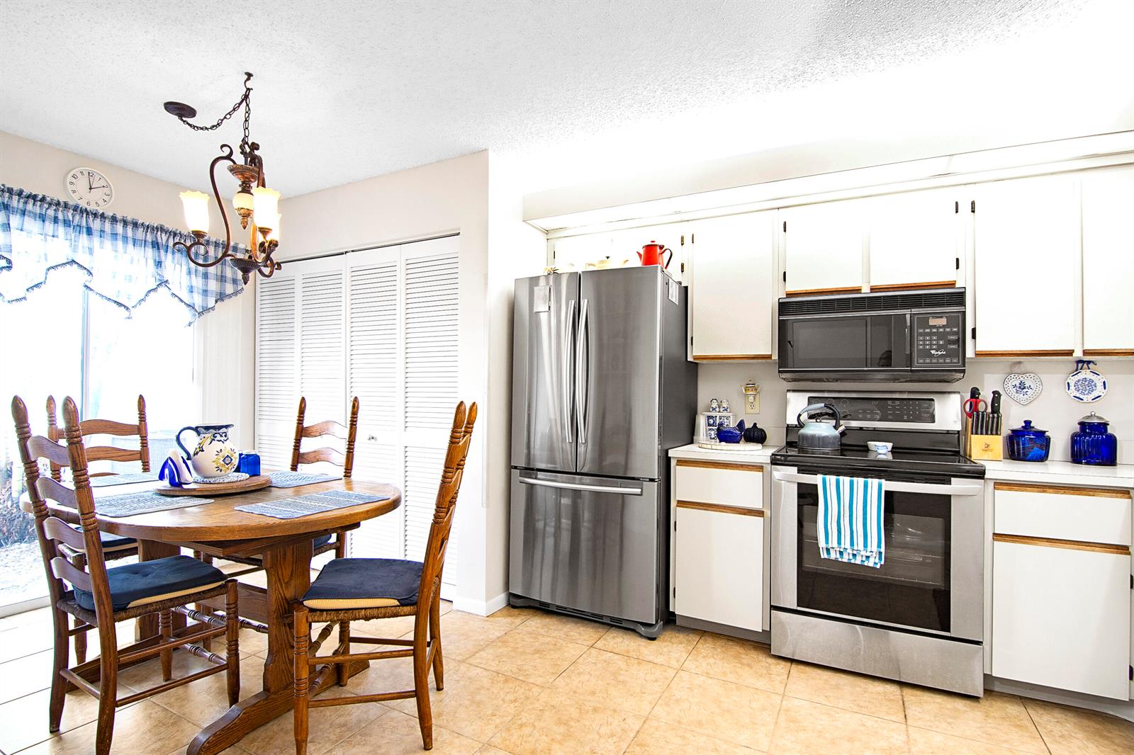A kitchen and dining area features white cabinets, stainless steel appliances, and a wooden table — 6198 Riverwalk Lane # 2, Jupiter FL 33458, JUPITER, FL
