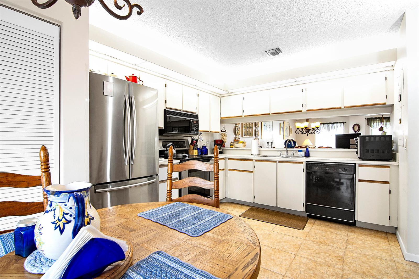 A kitchen with white cabinets, stainless steel appliances, and a round wooden dining table — 6198 Riverwalk Lane # 2, Jupiter FL 33458, JUPITER, FL