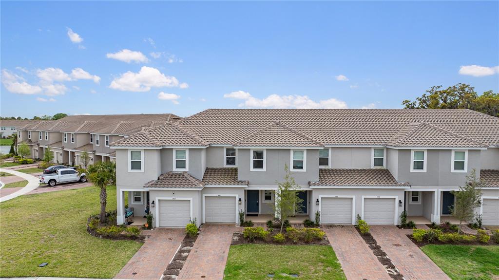 An aerial view shows a row of multi-story townhouses with gray siding and tiled roofs — 1406 ANCHOR BEND WAY, KISSIMMEE, FL