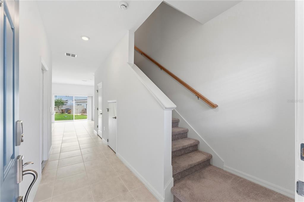 An entryway features tiled flooring, a carpeted staircase with a wooden handrail, and a doorway — 1406 ANCHOR BEND WAY, KISSIMMEE, FL