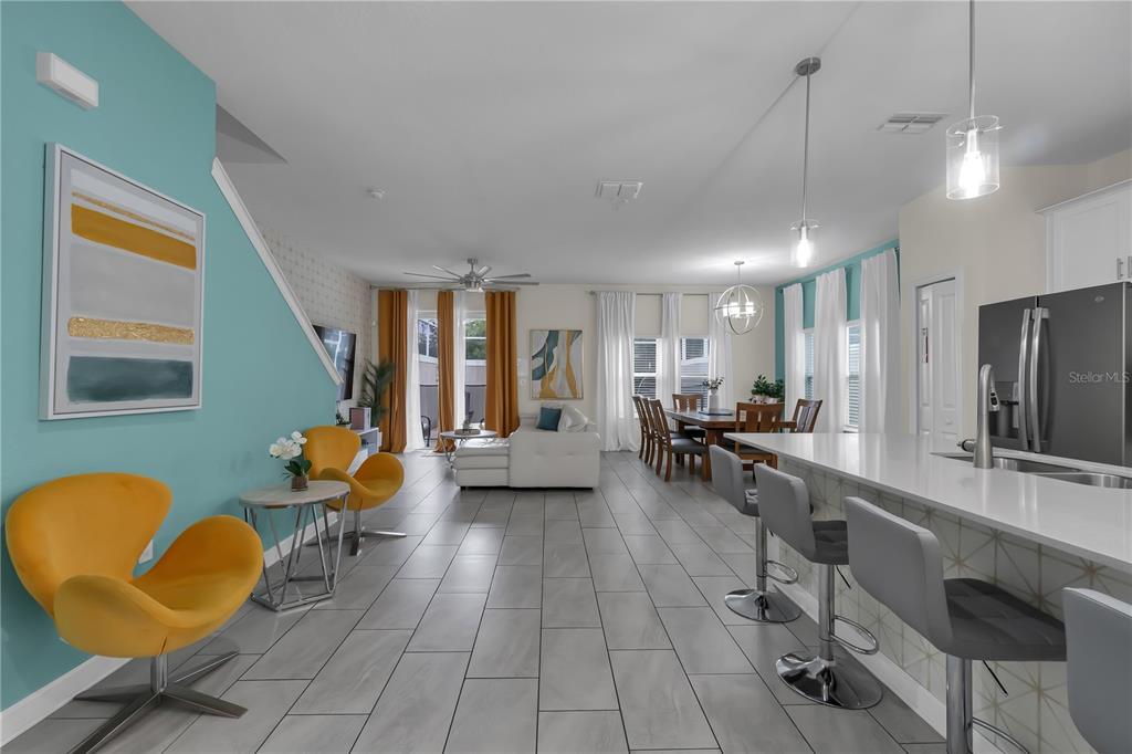 An open-concept living and dining area features gray tile floors, teal walls, and yellow chairs — 448 OCEAN COURSE AVENUE, DAVENPORT, FL