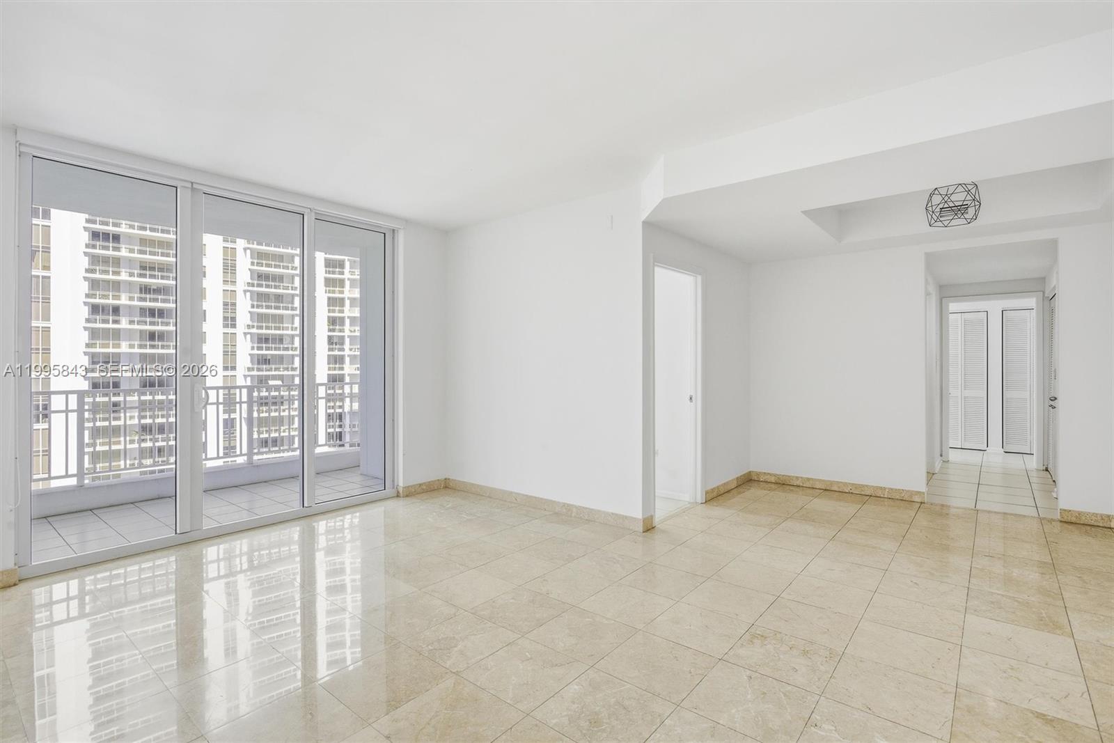 An empty room features beige tile floors, white walls, and a sliding glass door to a balcony — 801 Brickell Key Blvd # 1204, Miami FL 33131, MIAMI, FL
