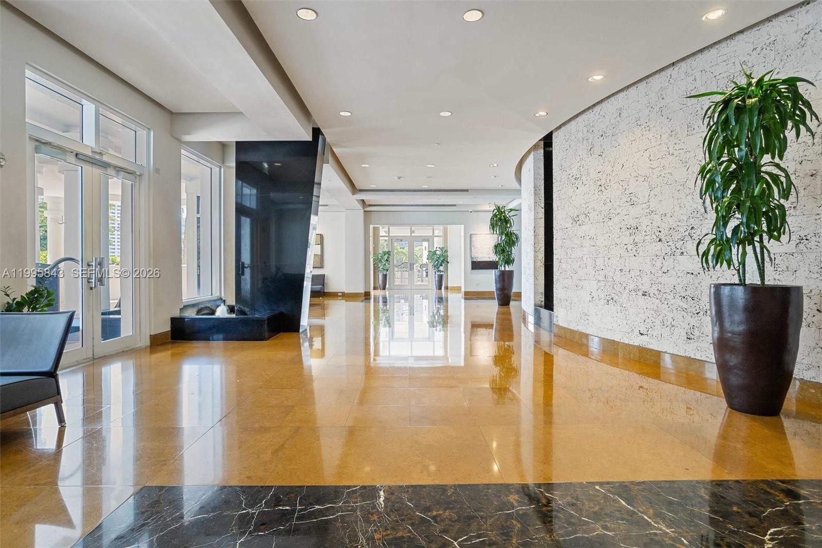 A spacious lobby features polished tile floors, a black marble water feature, and potted plants — 801 Brickell Key Blvd # 1204, Miami FL 33131, MIAMI, FL