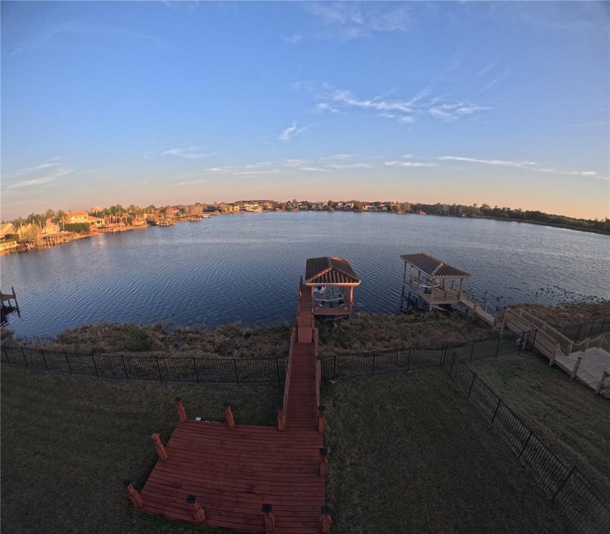 A wooden deck and pier extend into a lake with two covered boat docks — 1238 LAKE WHITNEY DRIVE, WINDERMERE, FL