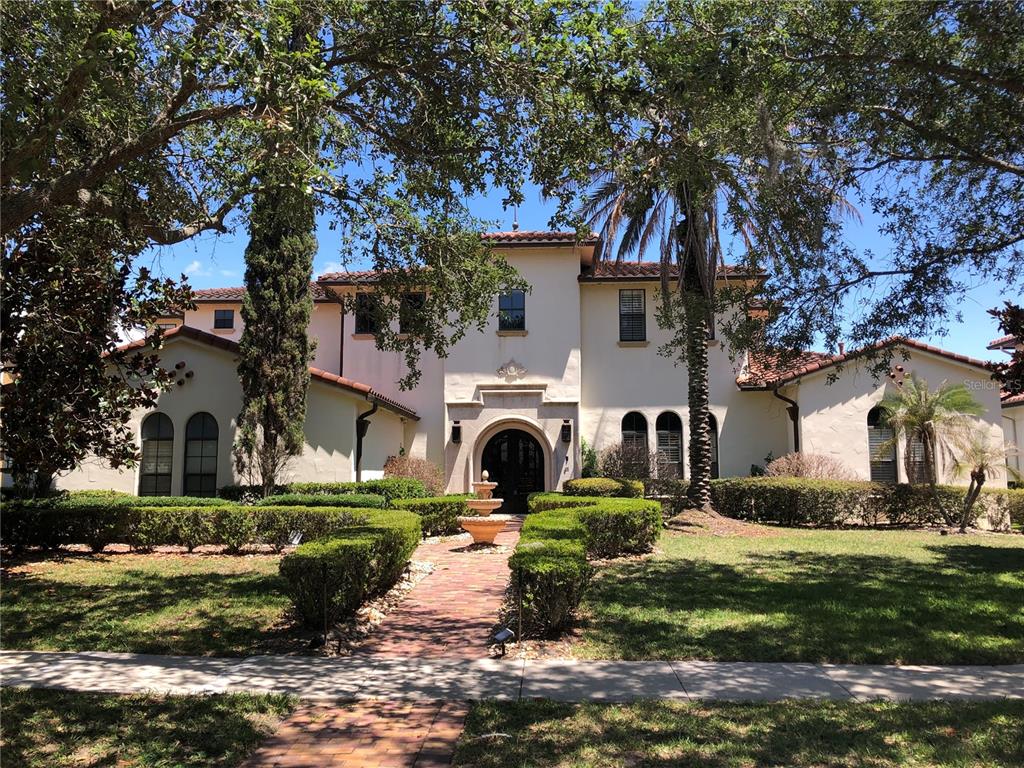 A two-story Mediterranean-style house features a brick walkway, a fountain, and manicured hedges — 1238 LAKE WHITNEY DRIVE, WINDERMERE, FL