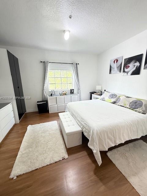A bedroom features a bed, white storage unit, wardrobe, and two white rugs on wood floors — 5610 NW 114th Pl # 202, Doral FL 33178, DORAL, FL