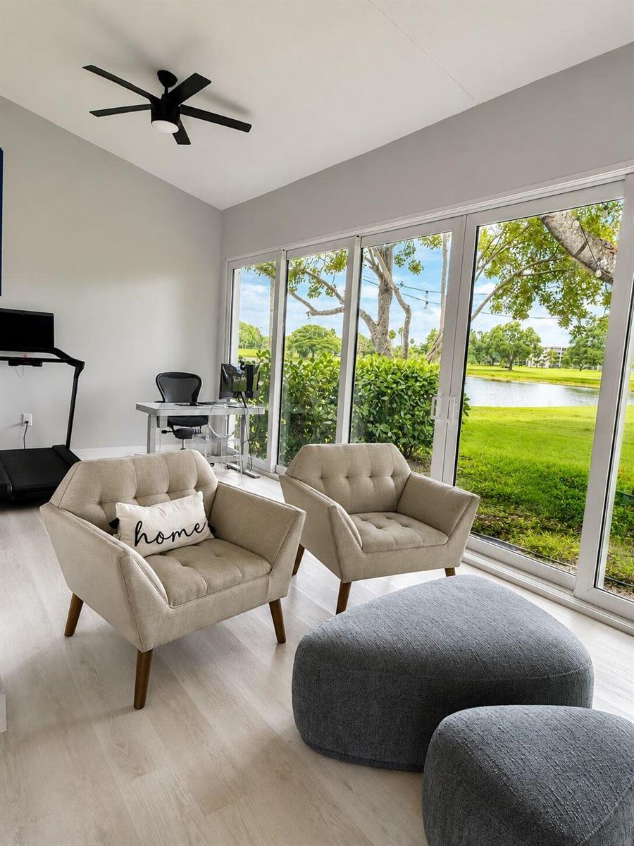 A room with two armchairs, two ottomans, a desk, and a treadmill overlooking a lake — 4103 Carriage Drive # H4, Pompano Beach FL 33069, POMPANO BEACH, FL