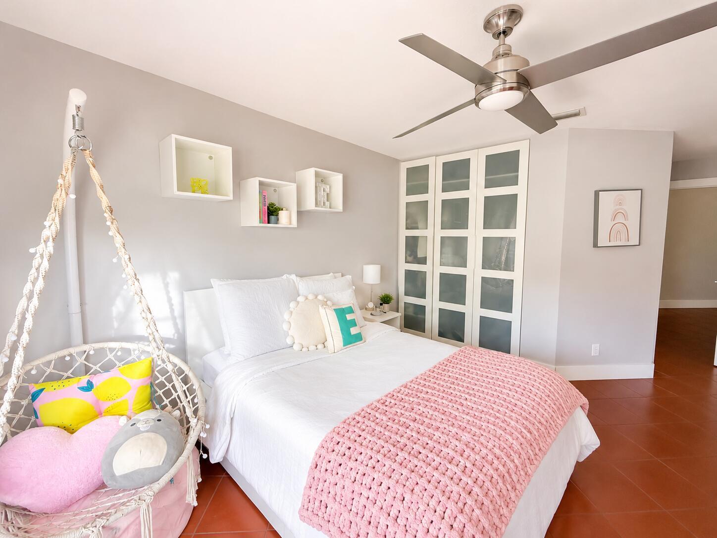 A bedroom features a hanging chair, a bed with pink bedding, and white wall shelves — 4103 Carriage Drive # H4, Pompano Beach FL 33069, POMPANO BEACH, FL