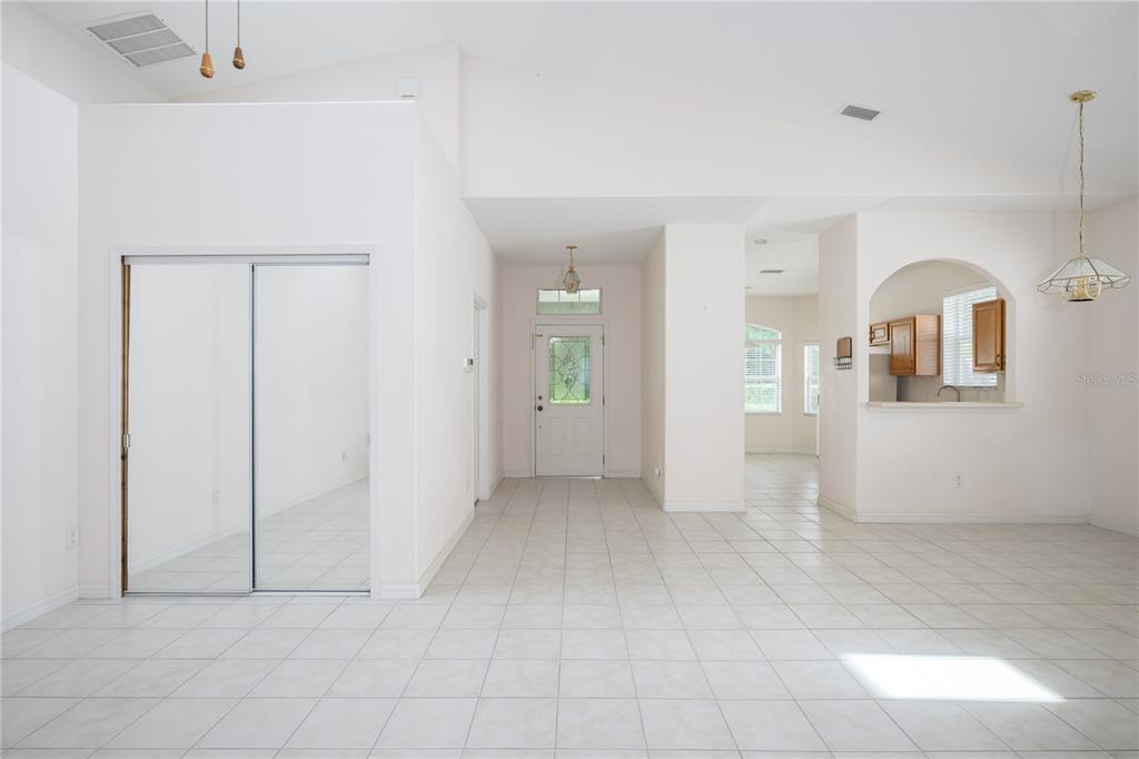 A bright, tiled entryway features a mirrored closet, a front door, and an arched kitchen opening — 708 CRESTWOOD DRIVE, ST AUGUSTINE, FL